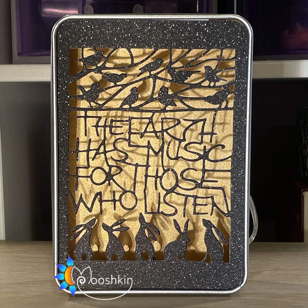 A die-cut message says "the earth has music for those who listen", in a light-up tin