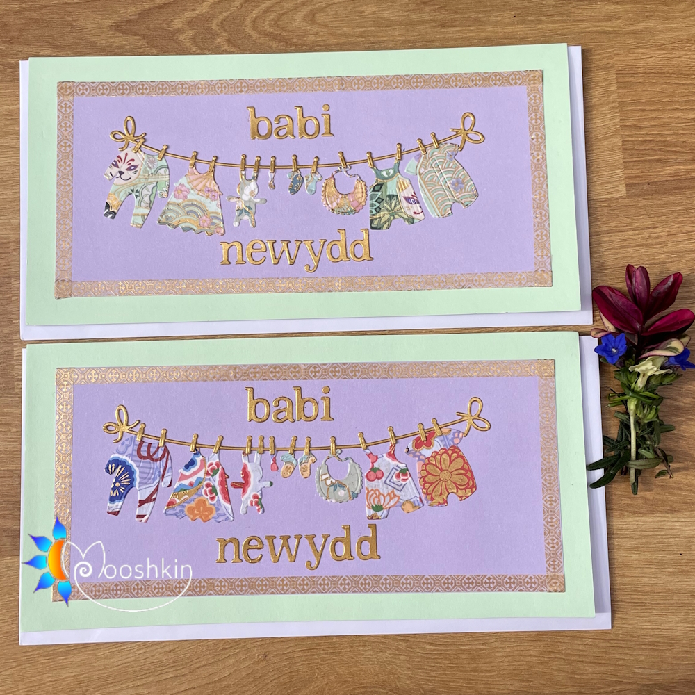 Handmade new baby cards in Welsh: little baby clothes hanging on a washing line, with the words 'babi newydd'
