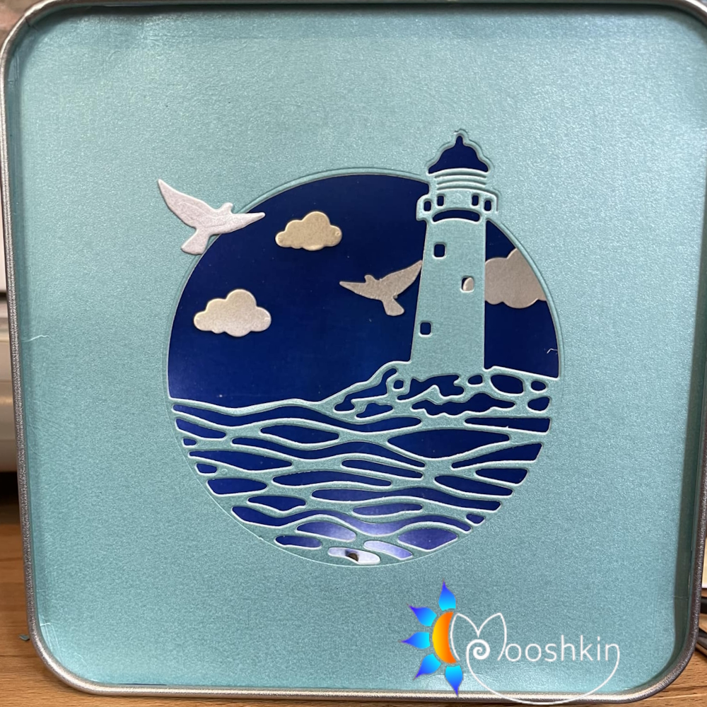Mooshkin Lantin - light-up scenes in tins - featuring a lighthouse and waves with clouds and birds.