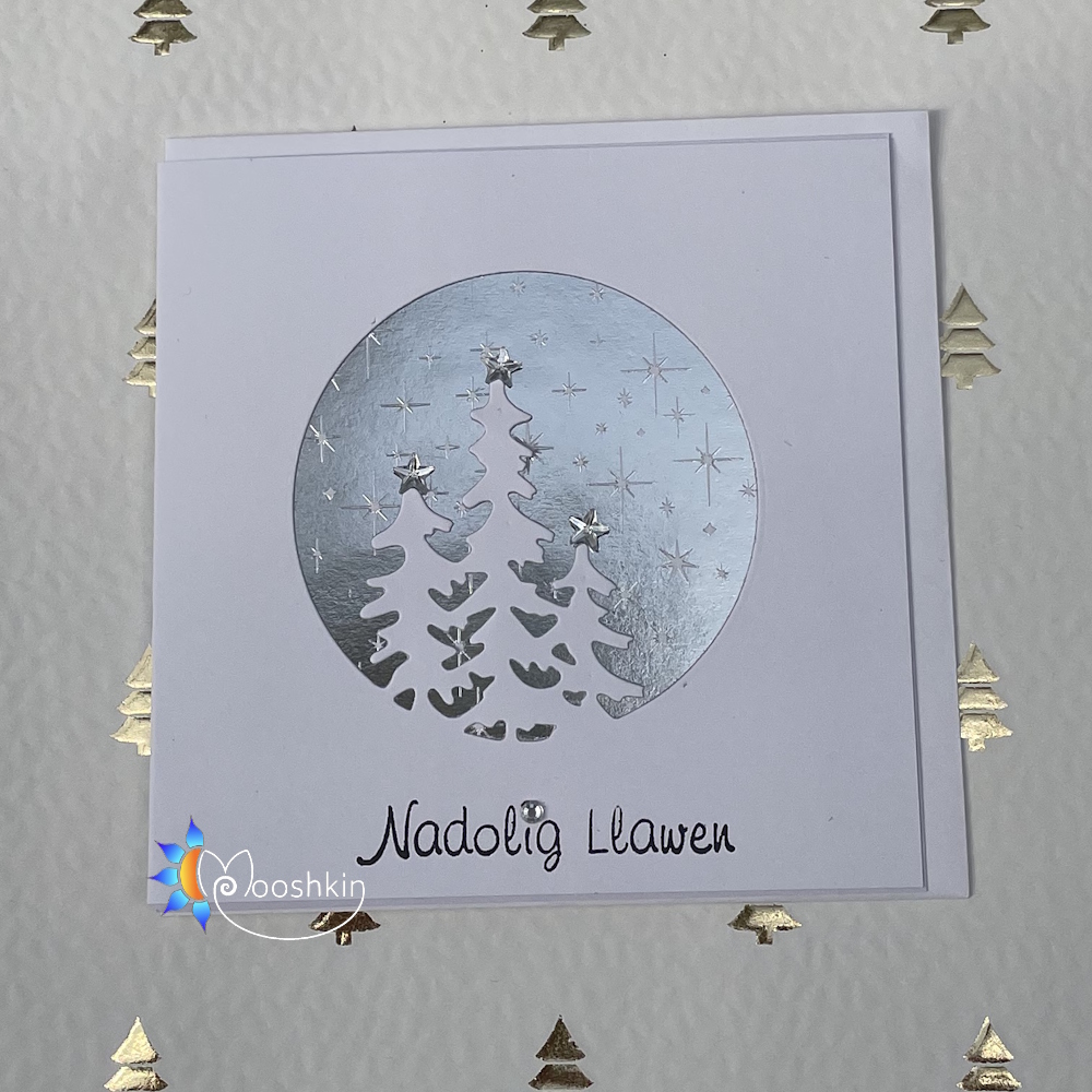 A handmade Christmas card featuring snowy trees backed by a starry sky